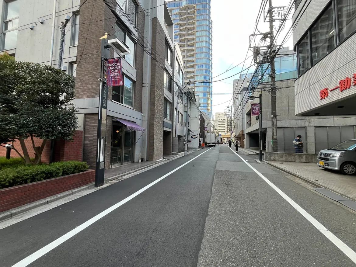 - 都市の商業エリアにある静かな路地、両側にはおしゃれな建物と電柱が立ち並び、通行人が行き交う風景