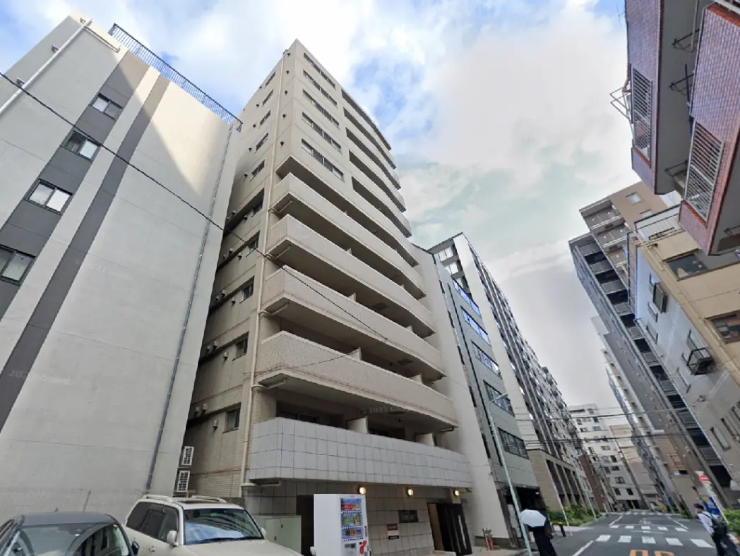 - 近代的なデザインのアパートメントビル、周囲には他の建物が並ぶ都市の風景、青空が広がる空間