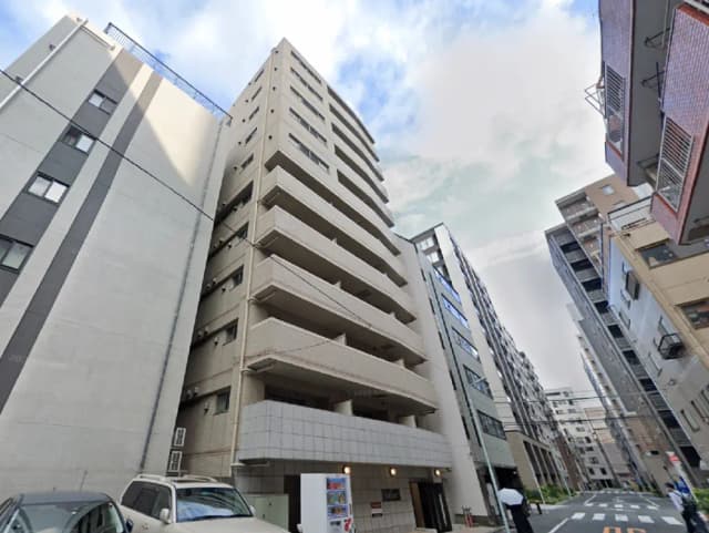 - 近代的なデザインのアパートメントビル、周囲には他の建物が並ぶ都市の風景、青空が広がる空間