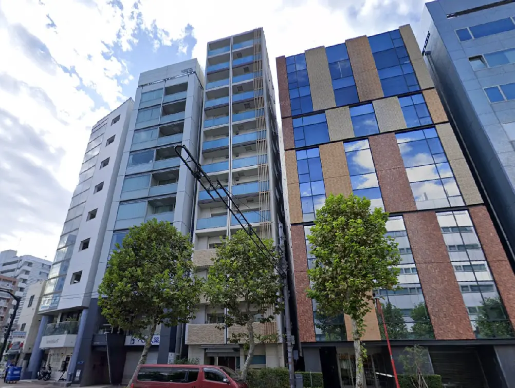 - 近代的なデザインの高層マンションとオフィスビル、緑豊かな街路樹と青空が広がる風景