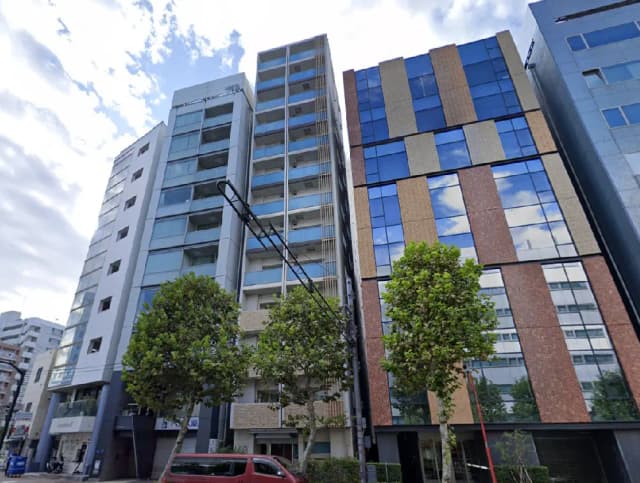 - 近代的なデザインの高層マンションとオフィスビル、緑豊かな街路樹と青空が広がる風景