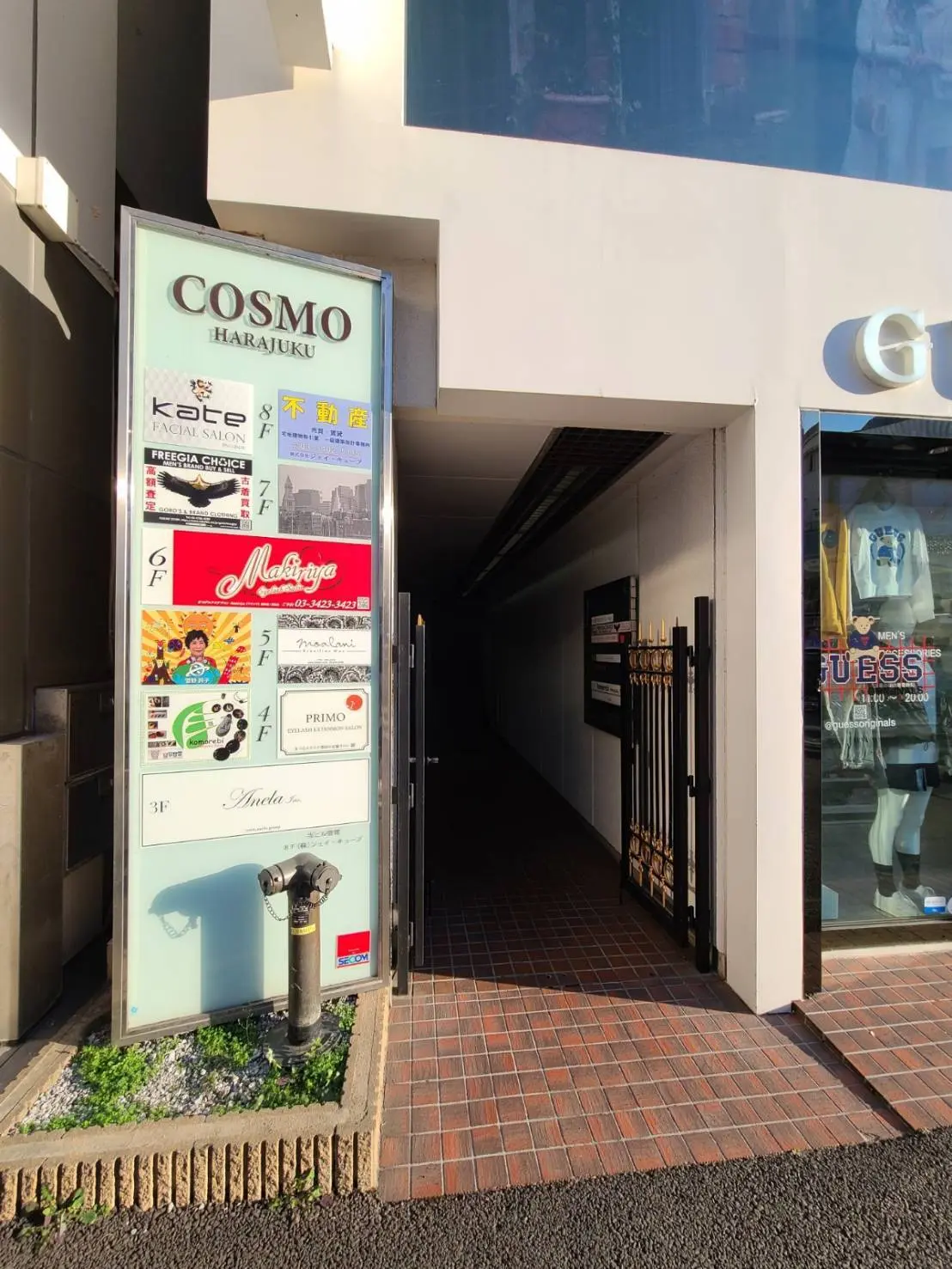 原宿の繁華街にあるビルの入り口と案内看板、ショップやサロンの広告が掲載された看板