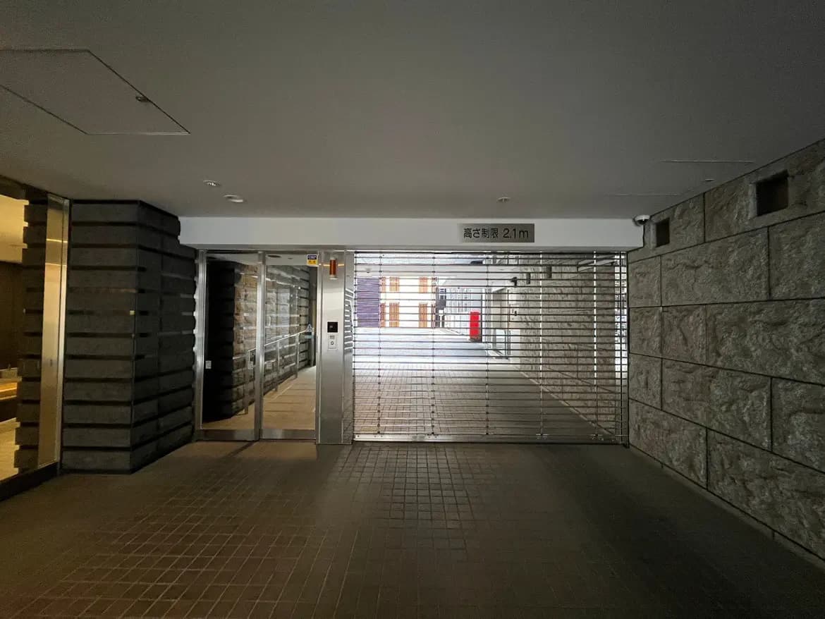 - モダンな建物のエントランス、中にシャッターがあり、入口の高さ制限を示す標識が取り付けられた光景