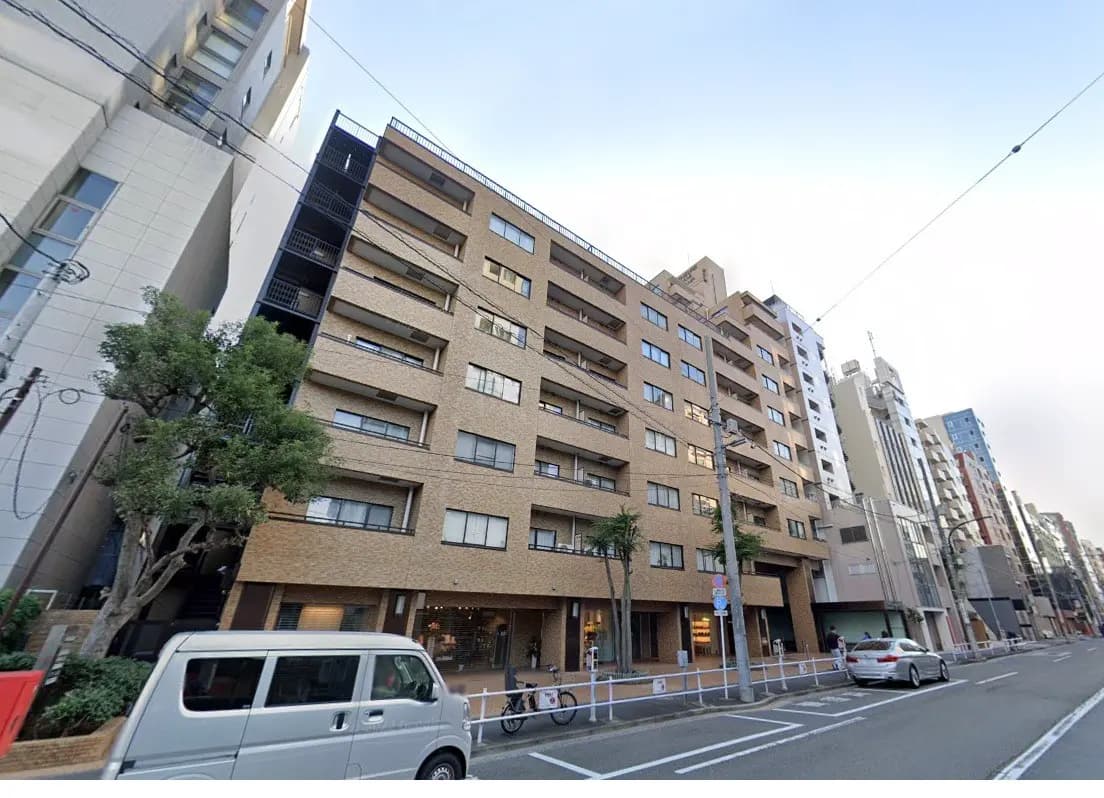 都市の通りに面したモダンなマンション建物、平日の交通と歩行者