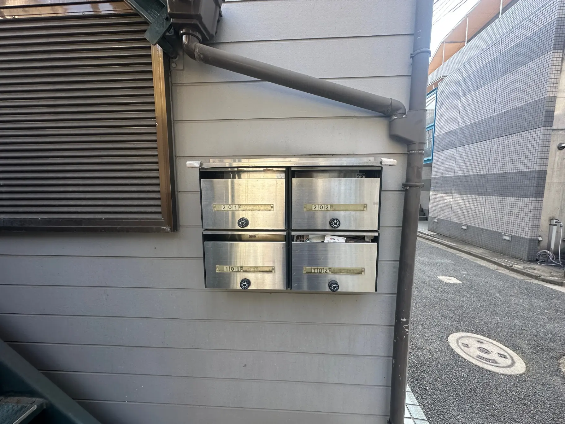 建物の壁に取り付けられたステンレス製のポスト、街角の背景