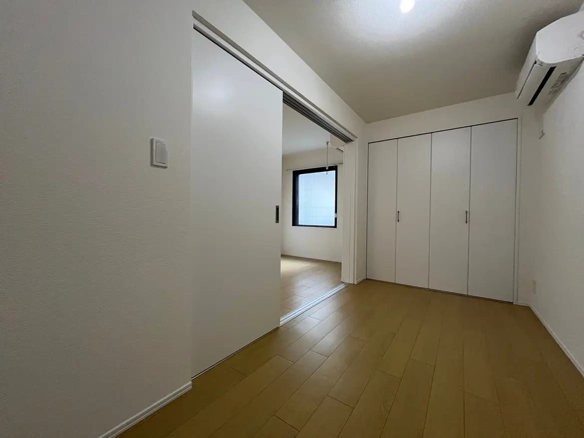 シンプルなデザインの空の部屋、明るい木製フローリング、白い壁と大きなクローゼット扉