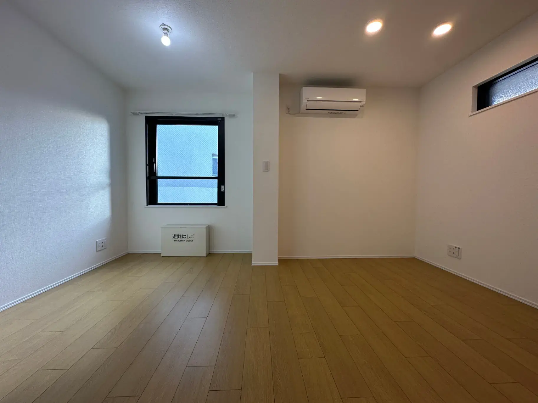 エアコン付きの明るい空間、木目調フローリングのシンプルな部屋