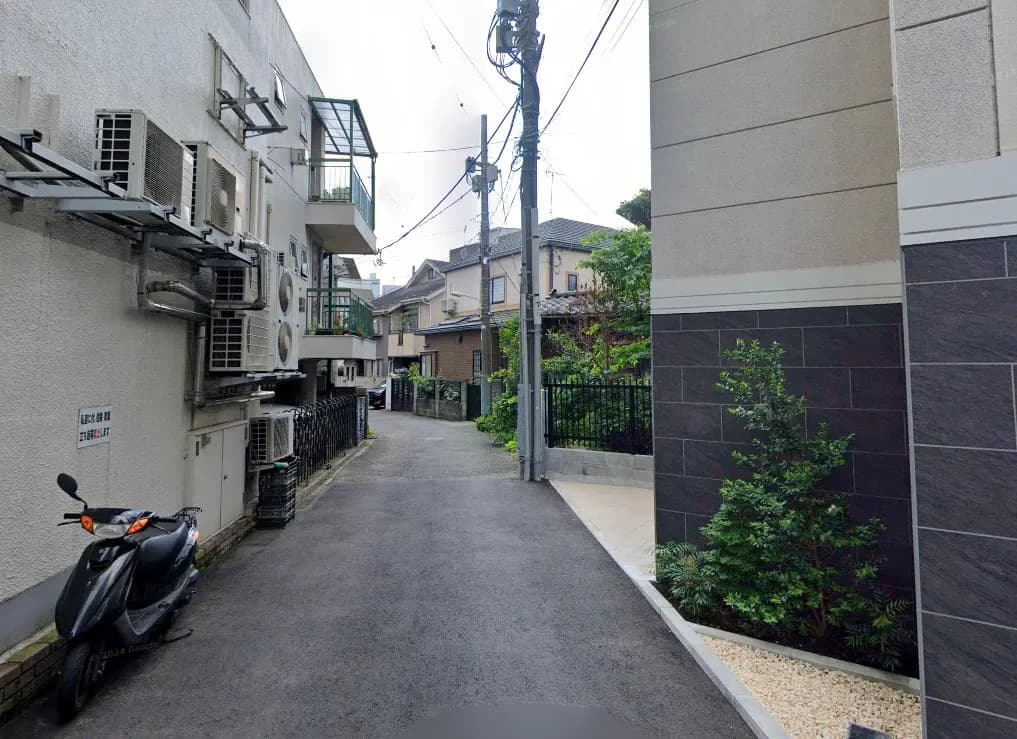 日本の住宅街の狭い路地、スクーターとエアコンの外部ユニットが並ぶ風景