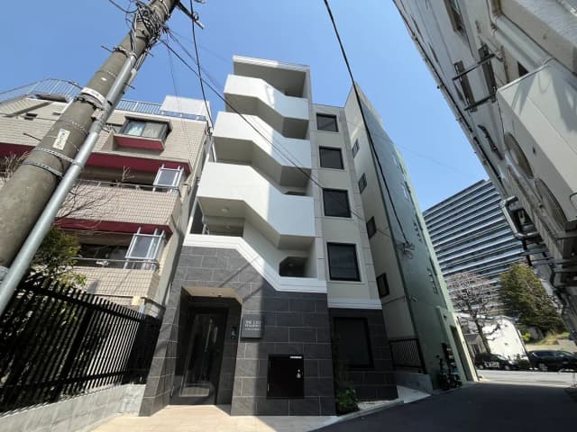 現代的な外観のマンション、都市の建物の隙間に位置する、黒と白のファサードデザイン