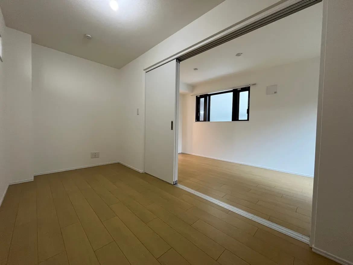 シンプルなデザインの空の部屋、木製のフローリングと白い壁、スライド式の扉と小さな窓があるインテリア