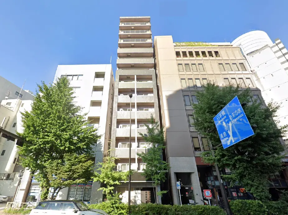 - 都市の中心に位置する高層住宅ビル、周囲には緑豊かな木々があり、青空が広がる風景