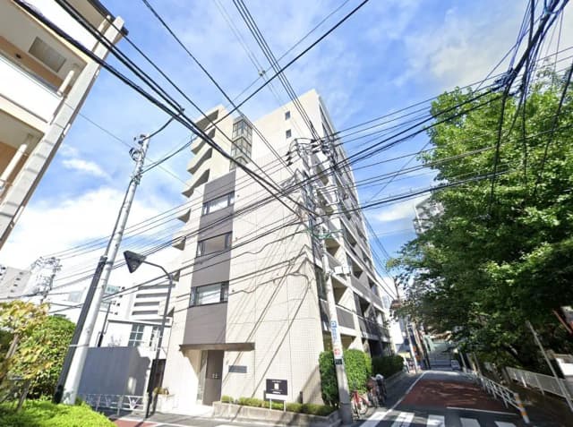 日本の都市部に位置するモダンなマンション、交差点、豊かな緑と多くの電線が特徴的な風景