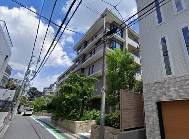 日本の住宅街の景色、晴れた日に撮影されたアパートと緑豊かな植栽、前面には電信柱と電線が見える