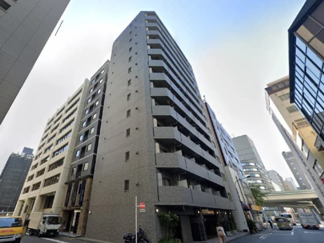 - 都心に立つ現代的な高層マンションの外観、周囲に他のビルが並ぶ街並みの景観