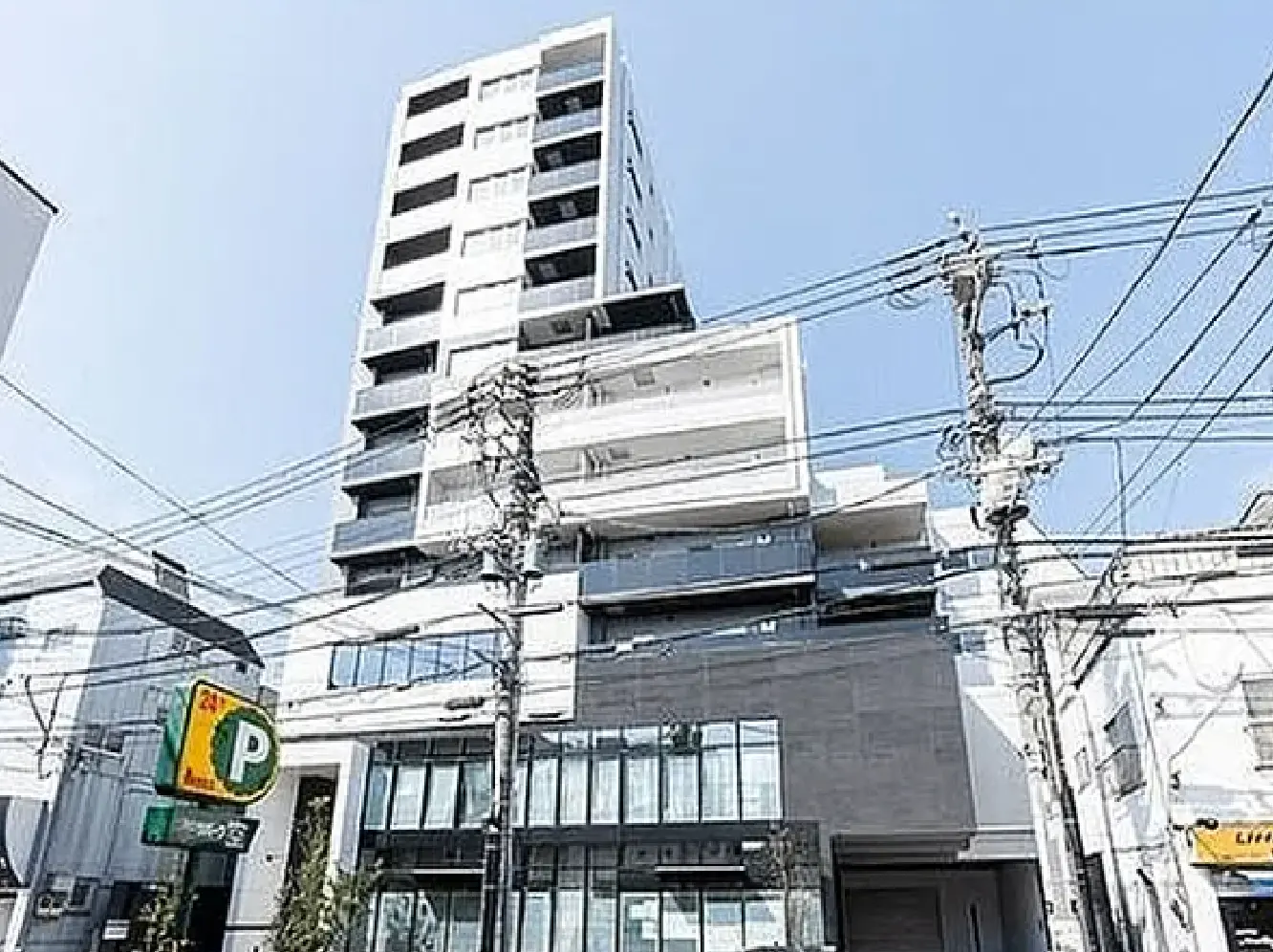 - 現代的なデザインの高層マンション、洗練された外観と大きな窓、青空の下に立つ様子