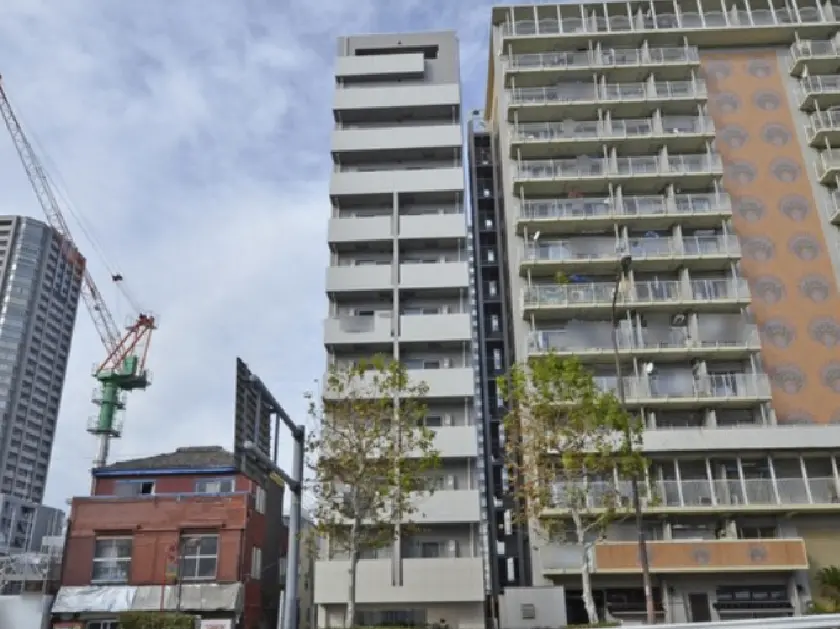 - モダンな高層マンションと建設中のクレーン、周囲の樹木が映える都市の風景