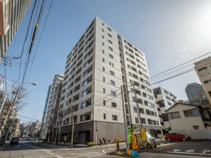 - モダンなデザインの高層マンション、青空を背景にした外観と周囲の街並みが映える画像