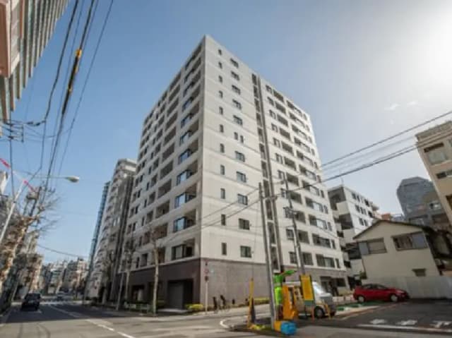 - モダンなデザインの高層マンション、青空を背景にした外観と周囲の街並みが映える画像