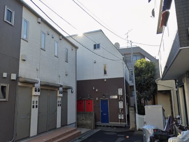 - 住宅街の中にあるモダンなアパートメント、特徴的な外観とカラフルなドアが並ぶエリアの風景