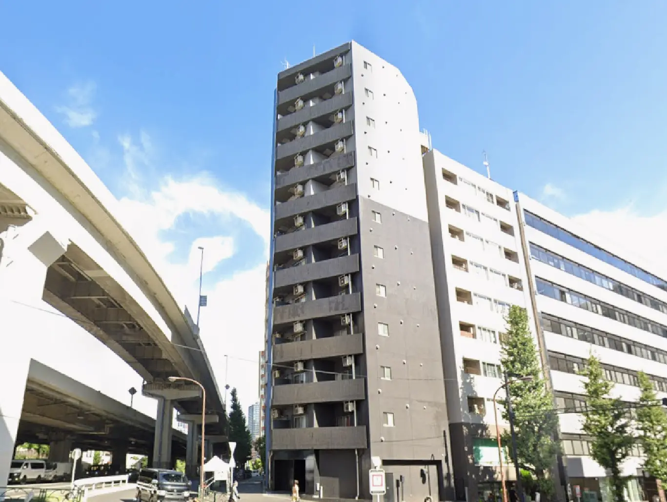 - 高層ビルの外観、近くに架かる高架道路と青空が広がる都市の風景