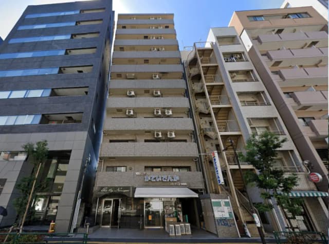 - 複数階建ての住宅ビル、入り口に「かていさんが」と書かれた看板、隣には異なるデザインの建物が並ぶ街並み