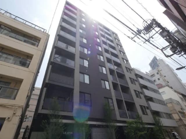 - 近代的なデザインの高層マンション、晴れた空の下で明るく照らされる外観と隣接する建物