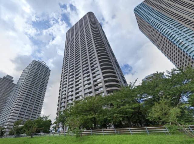 高層ビル群と青空、手前には緑豊かな公園が広がる都市景観の写真