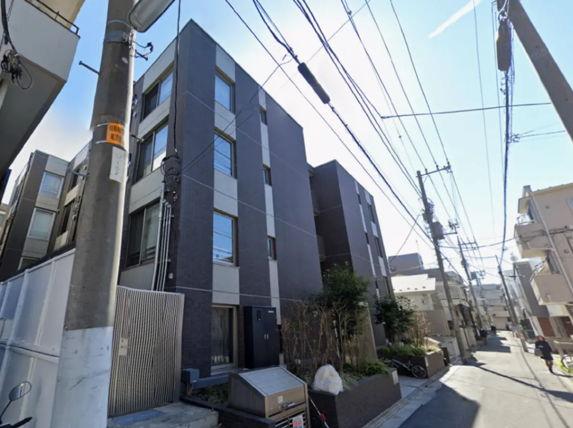 - モダンな外観のアパートメントビル、パワーラインと青空の背景、周囲には緑の植物が配置された街並み