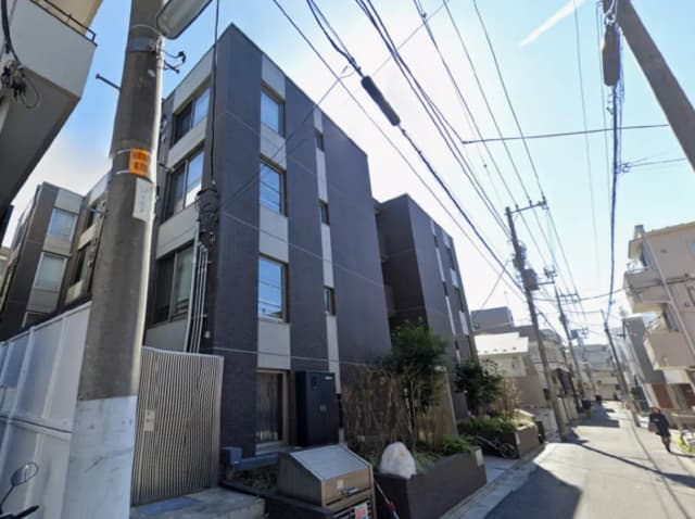 - モダンな外観のアパートメントビル、パワーラインと青空の背景、周囲には緑の植物が配置された街並み