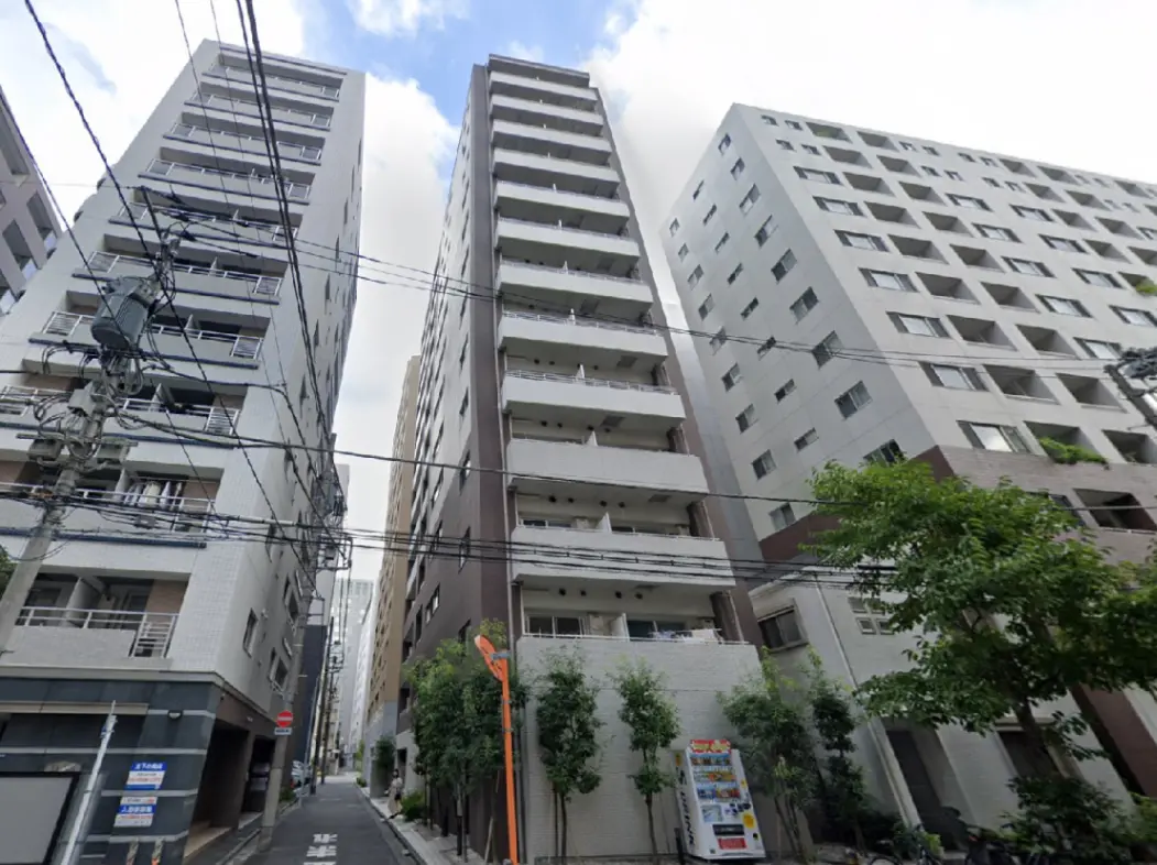 - 都市の高層ビル群、マンション入口には小さな木々と自動販売機が配置された風景