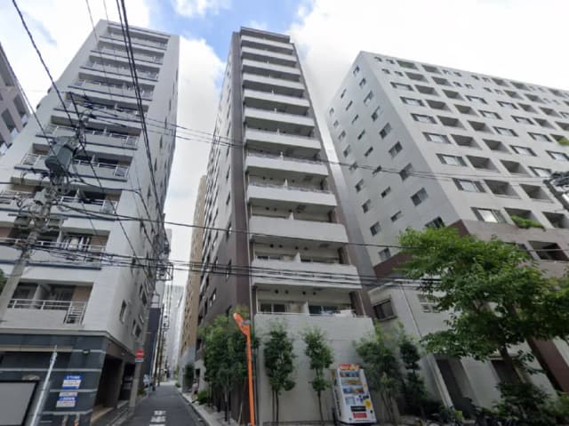 - 都市の高層ビル群、マンション入口には小さな木々と自動販売機が配置された風景