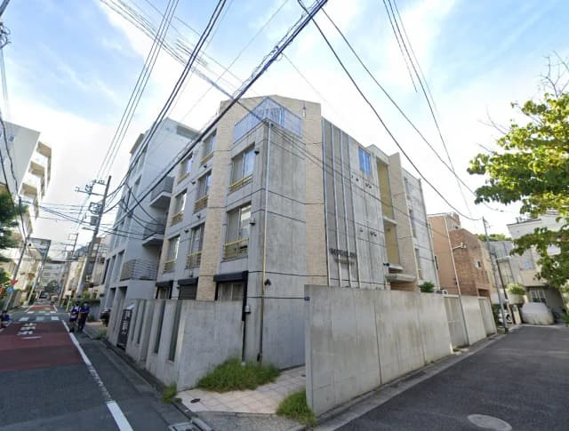都市の住宅街にある近代的なマンションの外観、晴れた日の青空と電線が交差する風景
