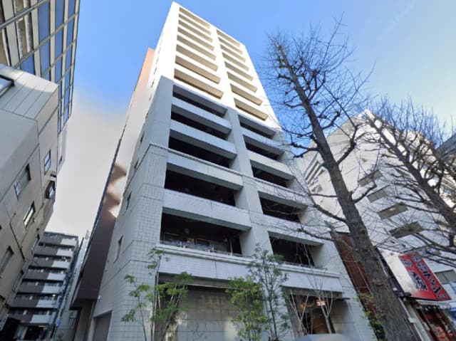 - 都市部に立つモダンなアパートメントビル、白いタイル張りの外観とバルコニー、周囲の建物との調和を見せるデザイン