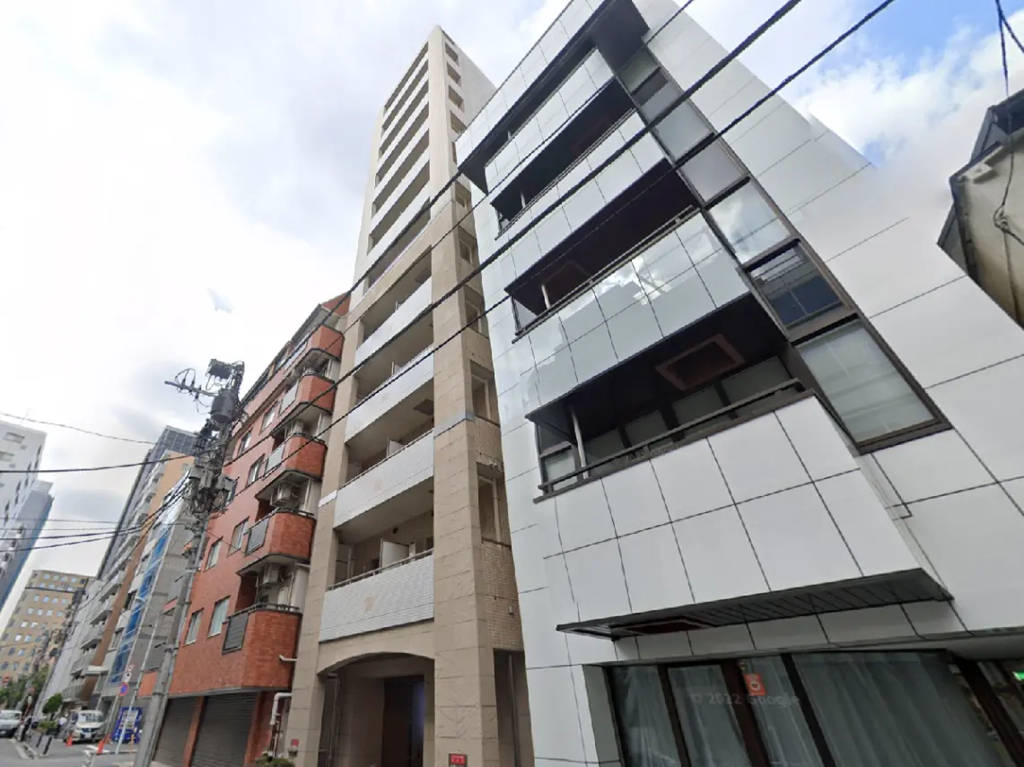 - 現代的なデザインのマンション外観、白いタイルとガラスを使用し、周囲の街並みに溶け込むスタイリッシュな建物