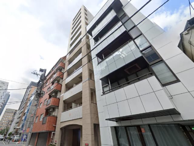 - 現代的なデザインのマンション外観、白いタイルとガラスを使用し、周囲の街並みに溶け込むスタイリッシュな建物