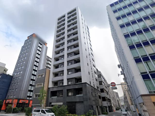 - 都市型の高層マンションとその周辺の建物、晴れ間のない空の下での街並みの風景