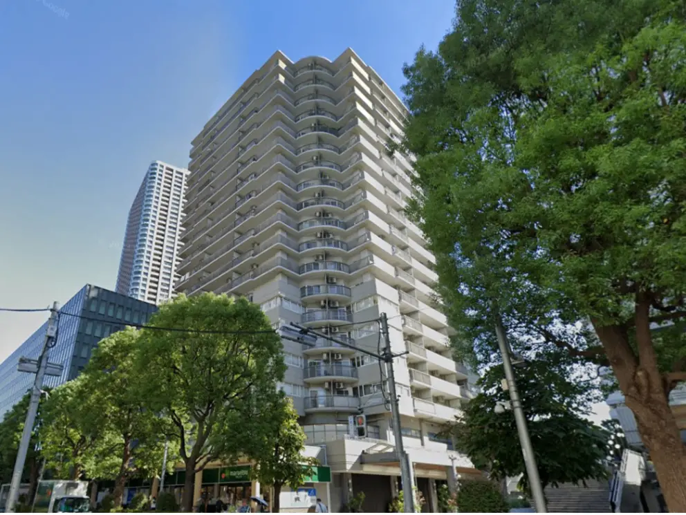 - 高層マンションの外観、新緑の木々と青空を背景にした現代的なデザイン