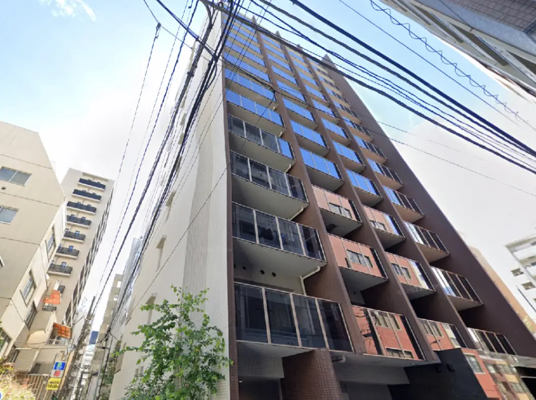 - モダンな外観の高層マンション、バルコニーと大きな窓が特徴、周囲には電線が見える都市の風景
