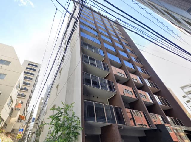 - モダンな外観の高層マンション、バルコニーと大きな窓が特徴、周囲には電線が見える都市の風景