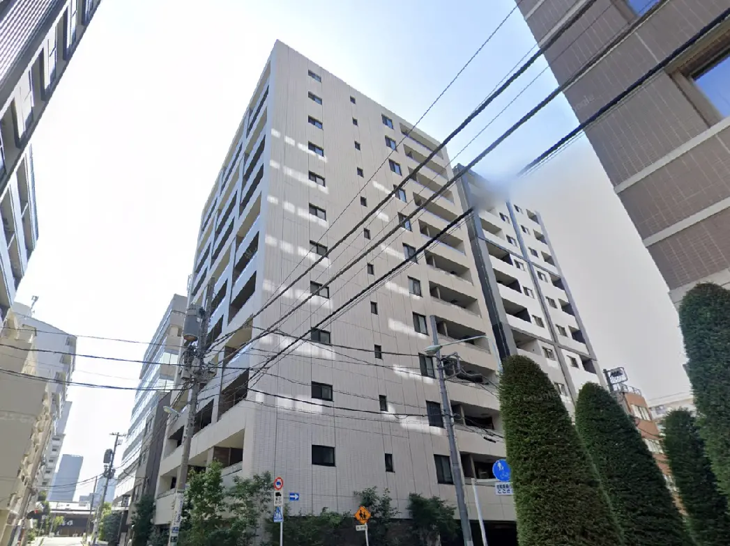 - 現代的なデザインの高層マンション、周囲に立ち並ぶビルや電柱が見える街並みの風景
