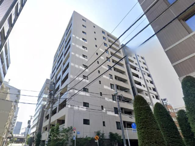 - 現代的なデザインの高層マンション、周囲に立ち並ぶビルや電柱が見える街並みの風景