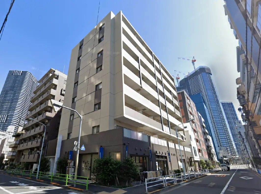 - 都市部に位置する現代的な5階建てアパートメント、隣接するビル群と青空の背景が印象的な風景