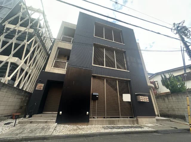 モダンな外観の都市型住宅、ダークカラーのファサード、隣に建設中の建物