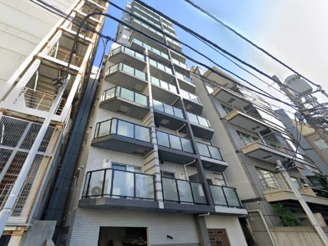 - 都市型マンションの外観、ガラスバルコニーと洗練されたデザインの6階建てビル、周囲に電線が走る景観
