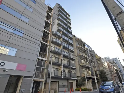 - 都市部にある現代的なデザインのマンション、バルコニー付きの6階建て、周囲には商業施設が立ち並ぶ景観