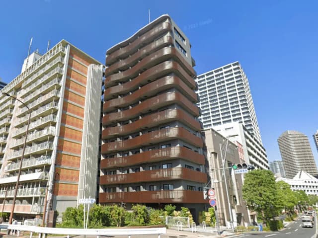 - モダンな外観のマンション、波形のバルコニーと近隣の高層ビルが特徴的な都市風景