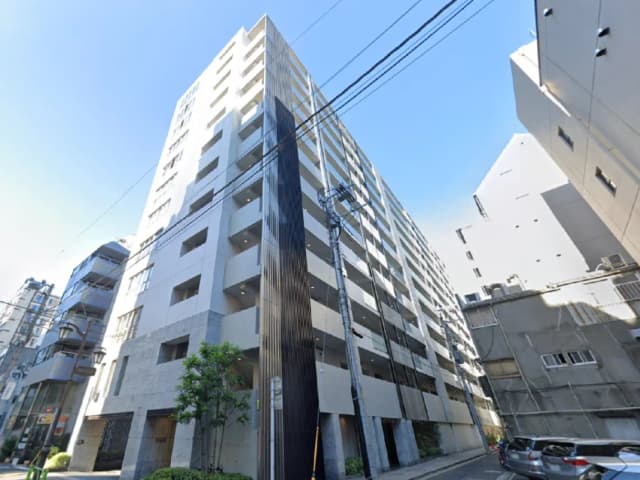- モダンな外観の高層マンション、周囲に高いビルと青空が広がる風景