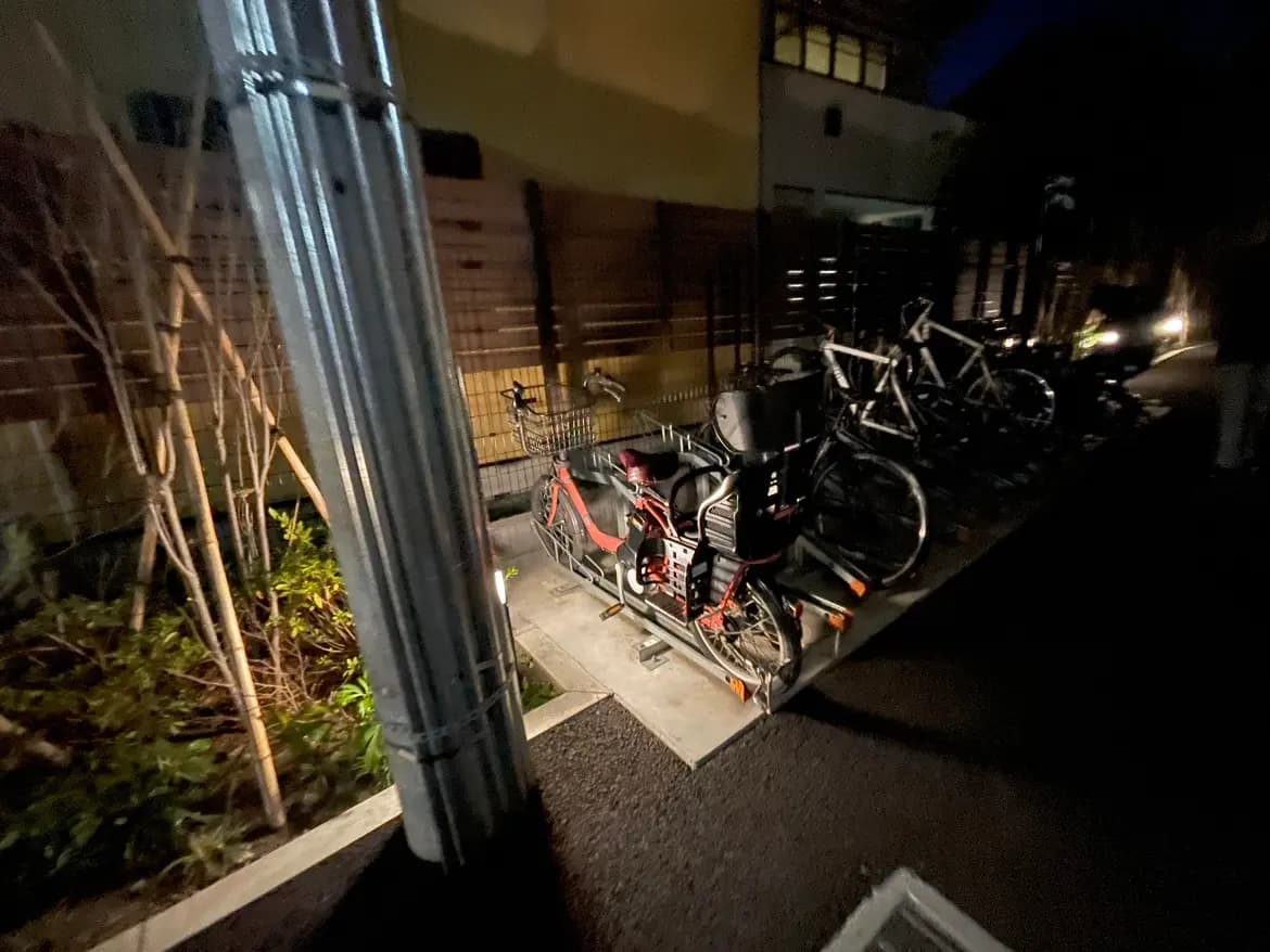 夜間の住宅街で停められた自転車、背景には街灯と建物が見える風景