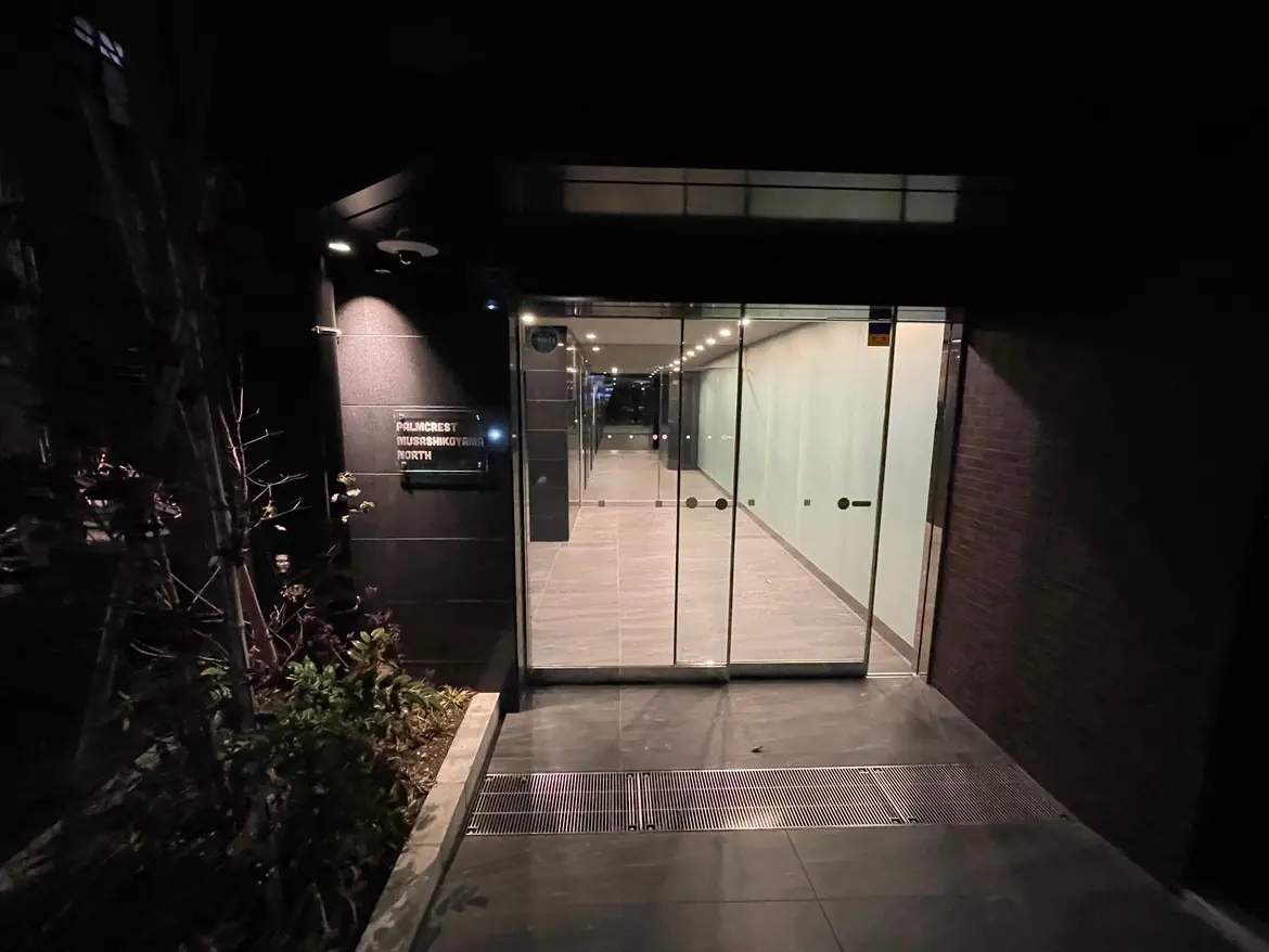 夜のモダンなオフィスビル入口、透明なガラス扉と外灯のある外観