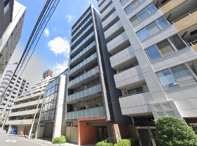 - 高層マンションの外観、ガラスバルコニーとシンプルなデザインが特徴的な建物、青空が広がる背景
